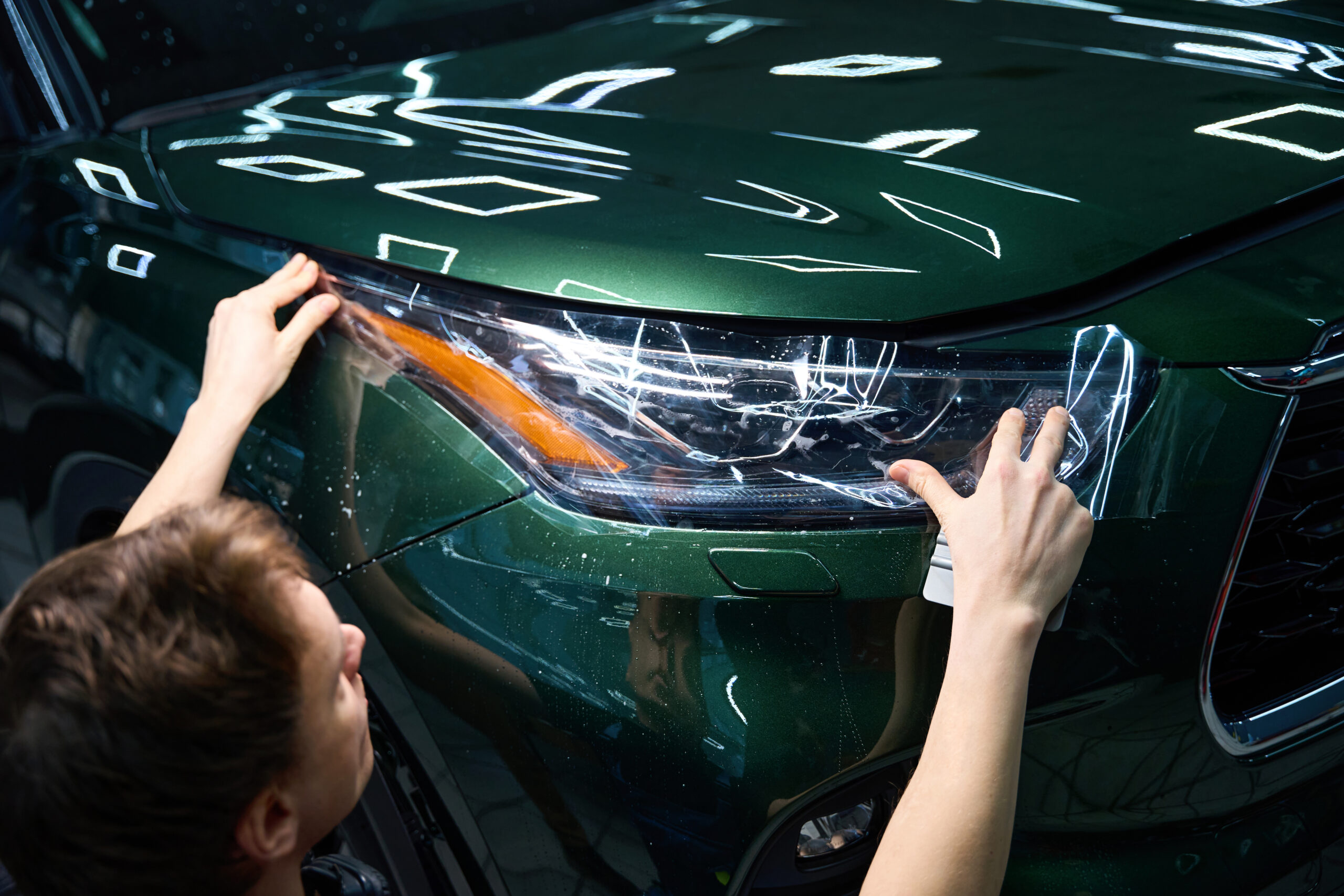 Certified technician applying paint protection film to a car in Al Quoz, Dubai